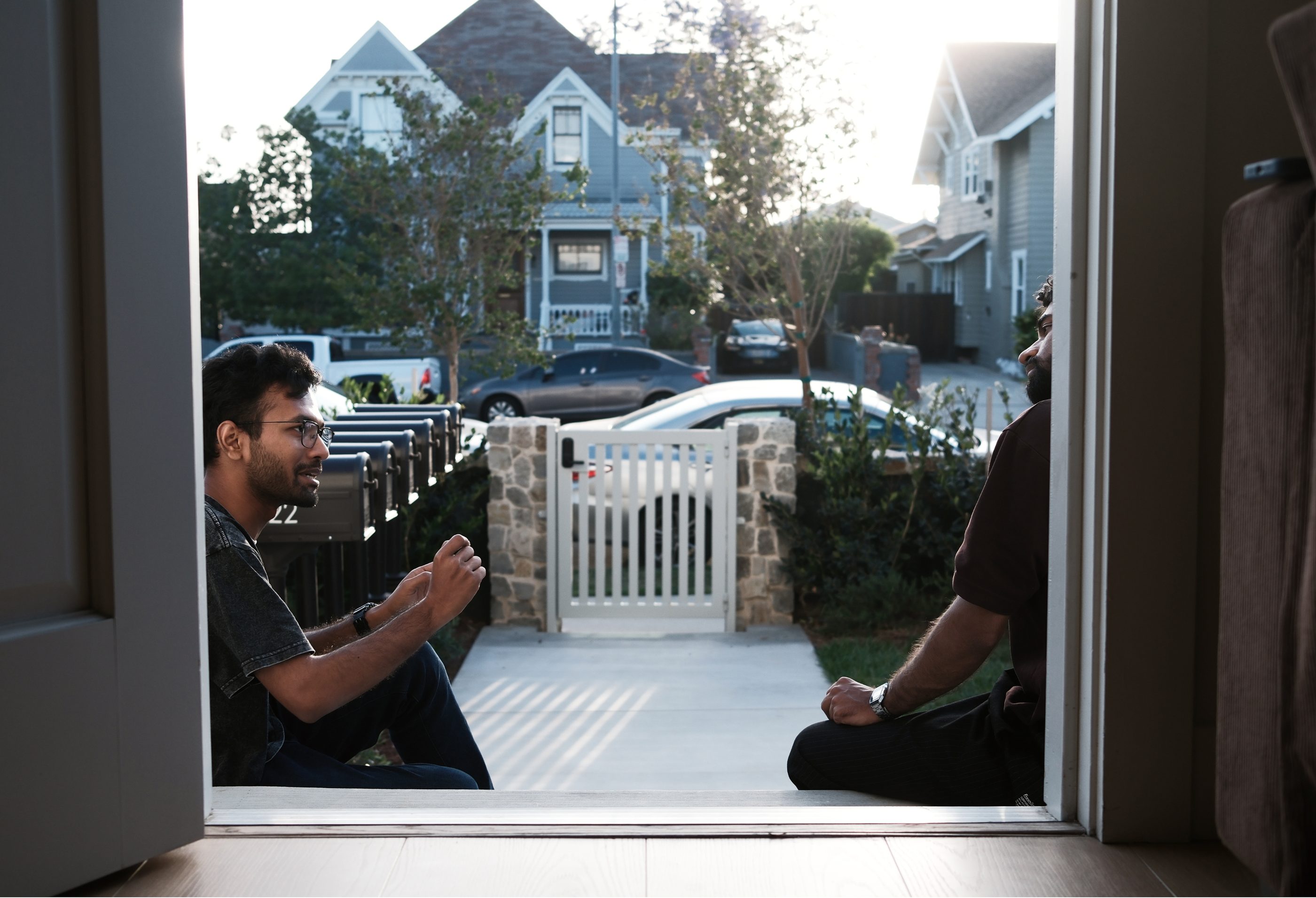 A man photographing through an open doorway toward houses across the street.